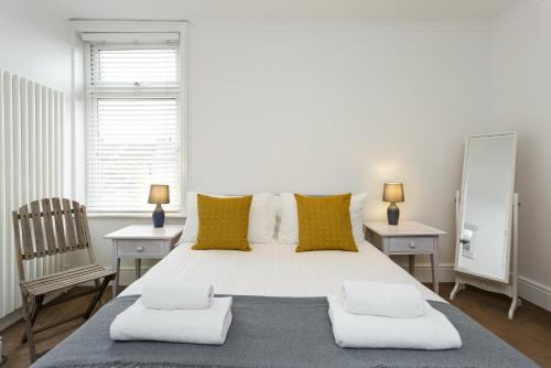 una camera da letto con un grande letto bianco con cuscini gialli di Percy Terrace - Charming 2 bedroom town house a Portsmouth
