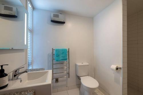 a white bathroom with a toilet and a sink at Mountain View Apartment in Wanaka