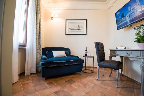 a living room with a blue chair and a desk at Castello Bonaria Wine & Spa Resort in Campiglia Marittima