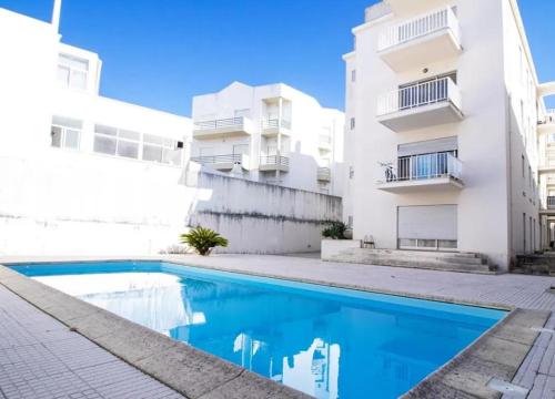 an apartment with a swimming pool in front of a building at Figueira Holidays in Buarcos