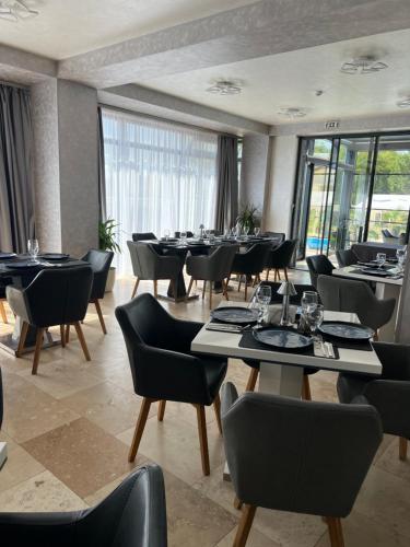 a dining room with tables and chairs and windows at Hotel Del Ponte in Târgovişte
