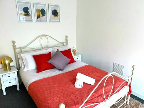 a bedroom with a red and white bed with red pillows at 4-bedroom home with off-road parking in Swansea