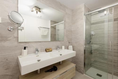 La salle de bains blanche est pourvue d'un lavabo et d'une douche. dans l'établissement Magnificent apartment, close to the beach, in Estepona, à Estepona
