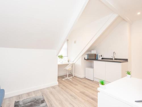 an attic kitchen with white walls and wooden floors at Pass the Keys The Couples Nest close to Leeds city centre in Leeds