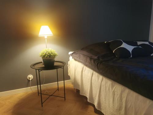 a lamp on a table next to a bed at Kaksio keskustan kupeessa in Jyväskylä