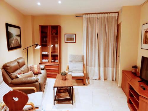 ein Wohnzimmer mit einem Sofa und einem Tisch in der Unterkunft Casa María, ático con vistas y parking in Sant Joan de les Abadesses