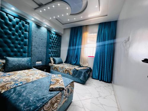 1 Schlafzimmer mit 2 Betten und blauen Vorhängen in der Unterkunft Superbe appart 3pieces a sania plage MARINA SMIR in Mʼdik