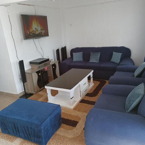 uma sala de estar com sofás azuis e uma mesa de centro em Bosslady Staycation C1 em Muchatha