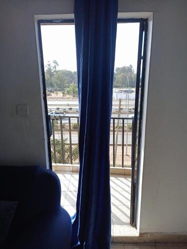 una puerta abierta a un balcón con una cortina azul en Bosslady Staycation C1 en Muchatha