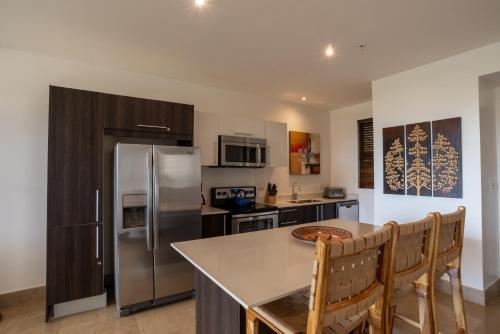 a kitchen with a stainless steel refrigerator and a table at Roble Sabana 404 Luxury Apartment Adults Only - Reserva Conchal in Playa Conchal