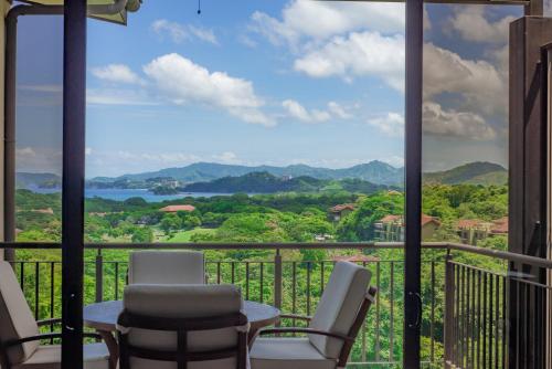 een balkon met stoelen en uitzicht op de bergen bij Roble Sabana 404 Luxury Apartment Adults Only - Reserva Conchal in Playa Conchal