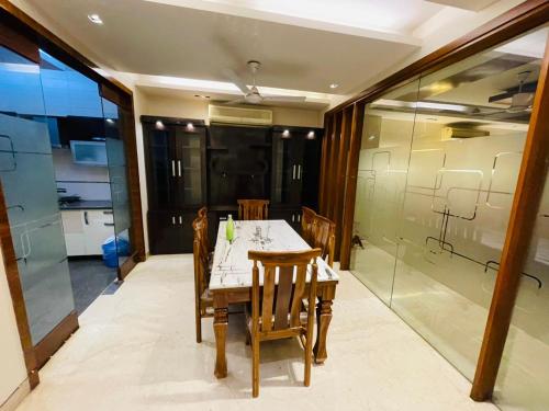 a dining room with a table and some glass walls at Divine India Service Apartment 4Bhk D-163 Saket in New Delhi