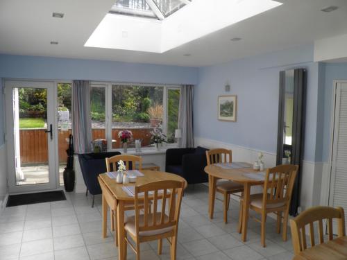 a dining room with tables and chairs and windows at Padog B&B in Llanrwst