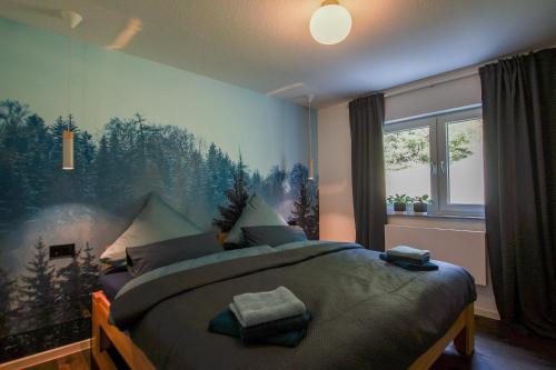 a bedroom with a large bed with a forest mural on the wall at Albsommer - Fehlatal Ferienhäuser in Burladingen