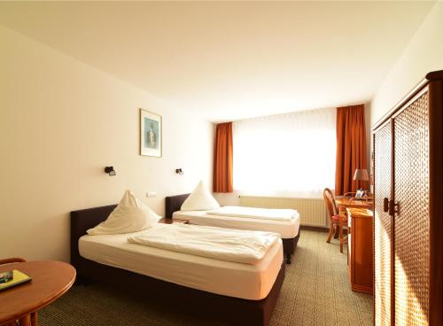 a hotel room with two beds and a desk at Land-gut-Hotel Schenkenberger Hof in Delitzsch