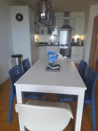 a white table with blue chairs in a kitchen at Fistral beach apartment in Newquay