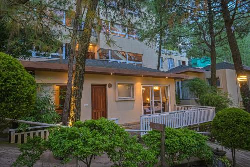 una casa con un portico bianco e un albero di Jungle Lodge Resort a Kasauli