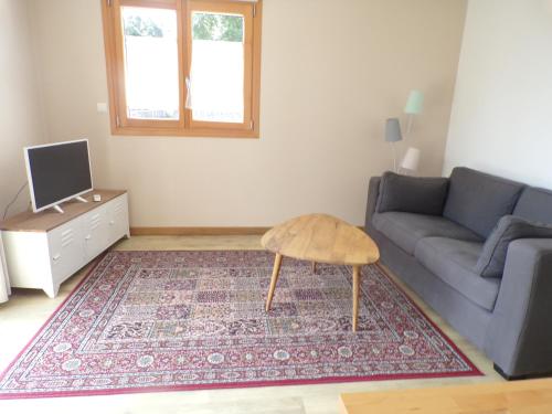 a living room with a couch and a table at Les clés du Vallion, T2 confort, bord de plage et paysages in Saint-Jouan-des-Guérets