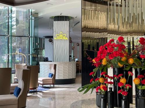 a lobby with vases of red flowers and chairs at Magnificent - Damac Distinction Downtown in Dubai