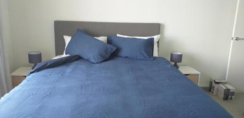 a bedroom with a blue bed with blue pillows at Apartment Twelve in Taupo