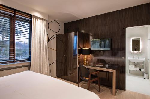 Schlafzimmer mit einem Bett, einem Schreibtisch und einem Waschbecken in der Unterkunft Hotel Groenendaal in Hoeilaart