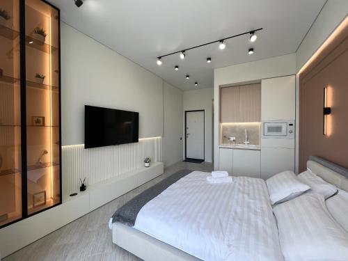 a bedroom with a large bed and a flat screen tv at LUX Апартаменты SMART #7 in Pavlodar