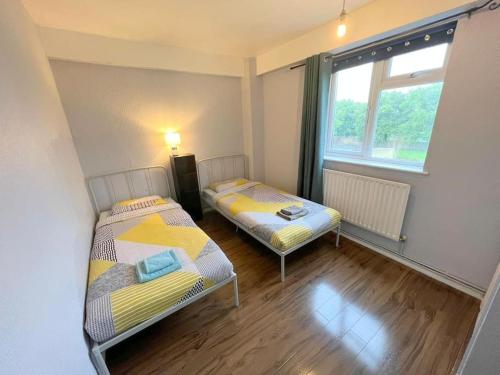 two beds in a small room with a window at 2-bedroom Flat in Sydenham in Forest Hill