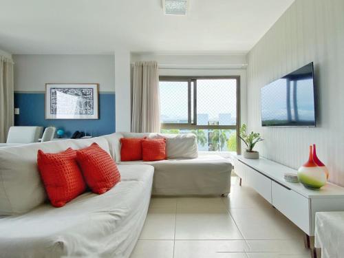 a living room with a white couch and red pillows at O Paraíso que você merece in Praia do Forte