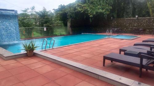 a swimming pool in a yard with chairs around it at Triose Boutique Hotel Lonavala in Lonavala