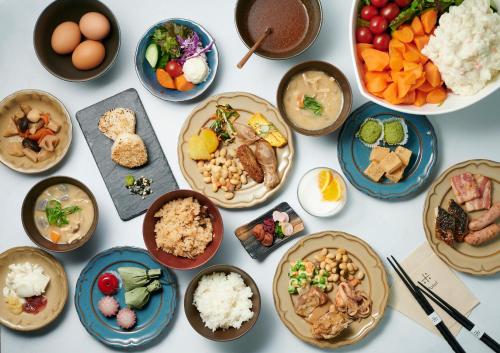 einen Tisch mit Teller mit Lebensmitteln und Schüsseln mit Lebensmitteln in der Unterkunft Umekoji Potel KYOTO in Kyoto