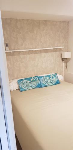Una cama con dos almohadas azules encima. en Sitges - Apartamento, en Sitges