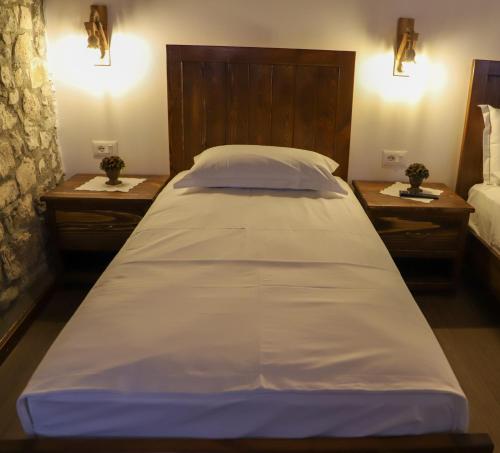 uma grande cama branca num quarto com duas mesas de cabeceira em Koroni Boutique Hotel em Berat