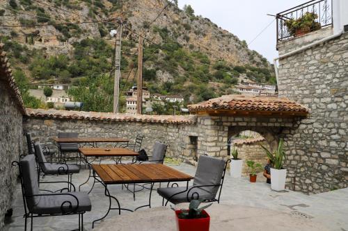 um pátio com mesas e cadeiras e uma parede de pedra em Koroni Boutique Hotel em Berat