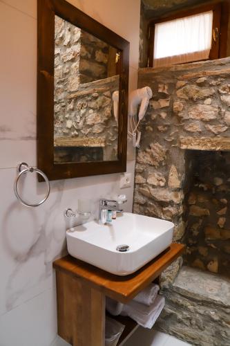 a white sink in a bathroom with a stone wall at Koroni Boutique Hotel in Berat