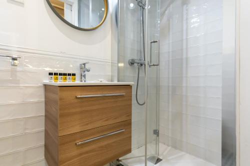 a bathroom with a shower with a wooden vanity and a mirror at Cozy studio - 1Bathroom - Chamberí in Madrid