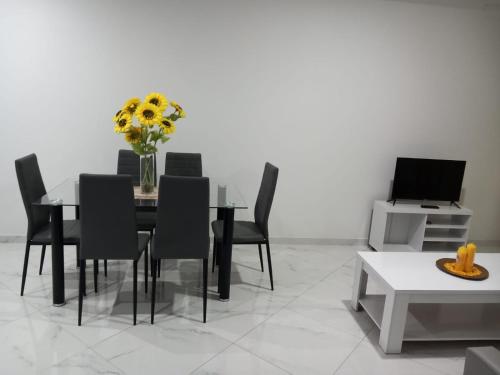 een eetkamer met een tafel en stoelen met een vaas met bloemen bij Edifício 2PALMA in Praia