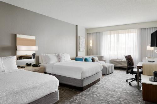 a hotel room with two beds and a desk at Courtyard Milwaukee Downtown in Milwaukee