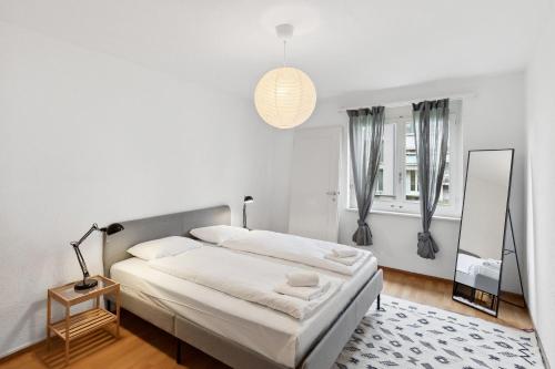 um quarto branco com uma cama e um espelho em Zurich Urban Charm: Your comfy stay close to the City em Zürich