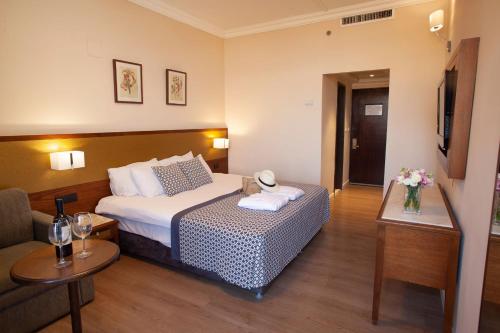 a hotel room with a bed and a couch at Caesar Premier Tiberias Hotel in Tiberias