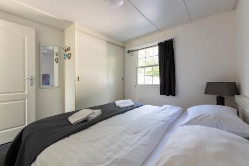 a bedroom with two white beds and a window at 16, Geniet van de rust, natuur & gratis parkeren! in Oisterwijk