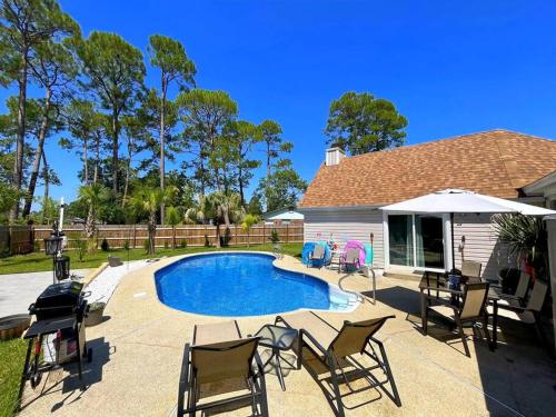 a backyard with a pool and chairs and a house at Very Private 3 Bed Home with HEATED Pool Palms and Big Fenced Yard in Pensacola
