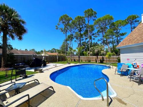a swimming pool with two chairs at Very Private 3 Bed Home with HEATED Pool Palms and Big Fenced Yard in Pensacola
