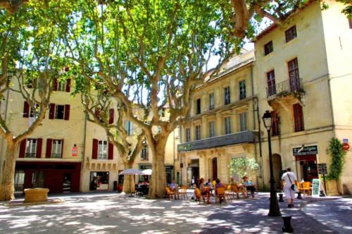 una calle en una ciudad con árboles, mesas y sillas en Appartement Belle-vue, en Beaucaire