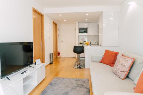 a living room with a white couch and a kitchen at Oporto Yellow Apartments in Porto