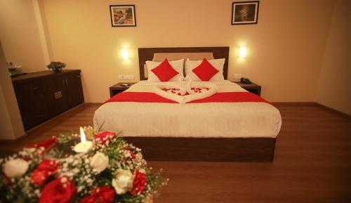 a bedroom with a large bed with red pillows and flowers at HOTEL ABAAM CHELSEA in Ernakulam