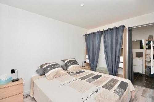 1 dormitorio con 1 cama con cortinas azules en Gîte le Mizériat - Appartement avec piscine privée, en Saint-Didier-sur-Chalaronne