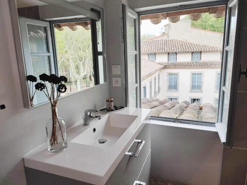 La salle de bains est pourvue d'un lavabo blanc et de 2 fenêtres. dans l'établissement Loft Chic Verdun / ConciergerieDameCarcas, à Carcassonne