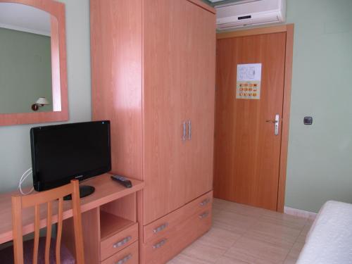 a bedroom with a tv and a wooden cabinet at Hostal Meseguer in El Altet