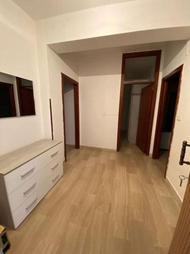 pusty salon z drewnianą podłogą i białymi szafkami w obiekcie NF appartamenti w mieście SantʼEufemia Lamezia