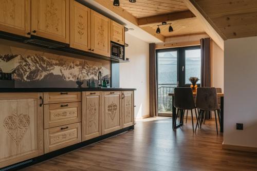 a kitchen with wooden cabinets and a table with chairs at Apartamenty Górajski Spa in Kościelisko